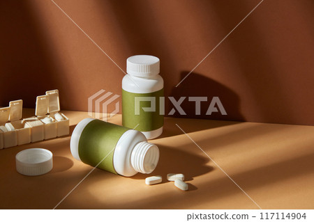 High angle shot designing template for advertising poster of vitamin or supplement product. Mock up bottle without label placed on yellow tabletop with a yellow pill box. Blank space for designing High angle shot designing template for advertising poster of vitamin or supplement product. Mock up bottle without label placed on yellow tabletop with a yellow pill box. Blank space for designing 117114904