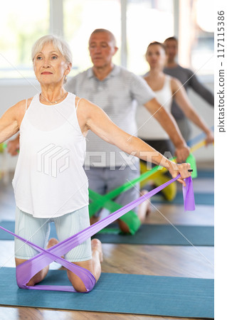 Elderly woman exercises with pilates band Elderly woman exercises with pilates band 117115386