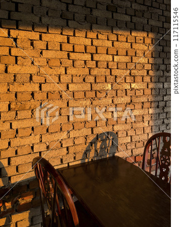 A wall with a table and chairs indoors with a red sunset shining through a window. A wall with a table and chairs indoors with a red sunset shining through a window. 117115546