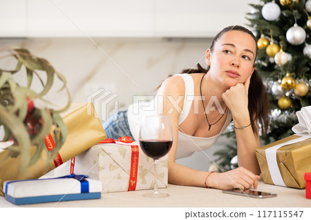 pensive young girl stands among New Year s gifts pensive young girl stands among New Year s gifts 117115547