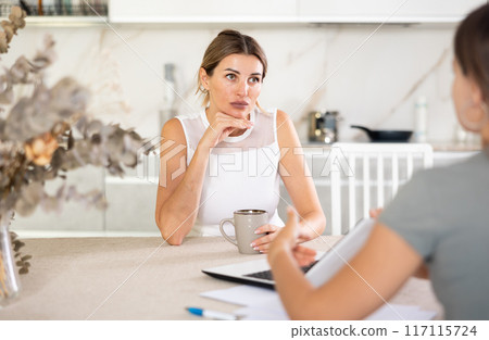 Woman talks to anb agent while sitting at table in kitchen Woman talks to anb agent while sitting at table in kitchen 117115724