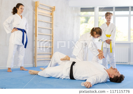 Judo or jiu jitsu classes - family with two children practicing grabbing and throwing on sports mats 117115776
