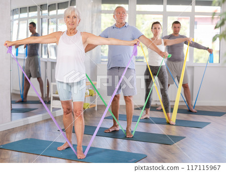 Elderly woman exercises with pilates band 117115967