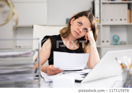 Portrait of tired woman bookkeeper sitting at table 117115978