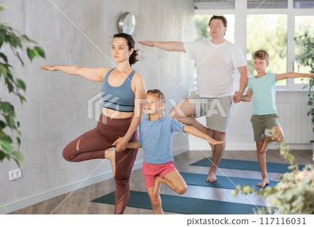 Harmonious family members practicing tree pose in pairs 117116031