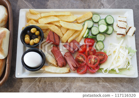 Delicious Breakfast Dish with Fresh Vegetables, Cheeses, Sausages, and Fried Egg 117116320