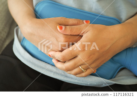 woman using hot water bag for period pain 117116321