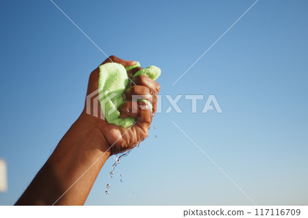 slow motion of Hands squeeze wet towel against blue sky. draining water from wet towel.. 117116709