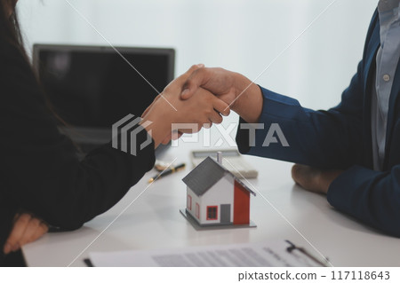 Estate agent shaking hands with customer after contract signature 117118643