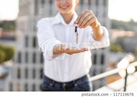 Woman holding house keys in urban setting Woman holding house keys in urban setting 117119676