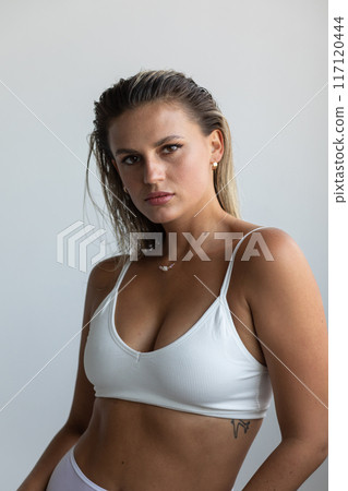 Beautiful blonde in white lingerie posing on white background 117120444