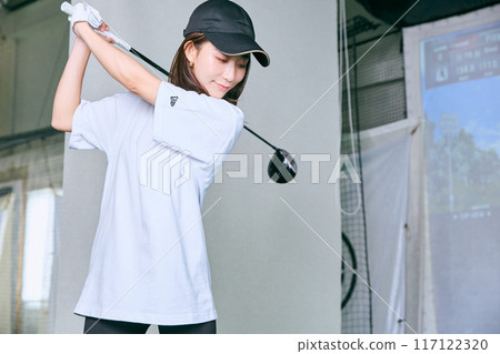 一名女子在室內高爾夫練習場練習 117122320