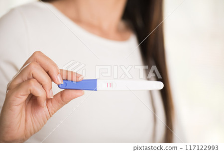 Woman with pregnancy test positive result, focus on foreground 2 stripes. 117122993