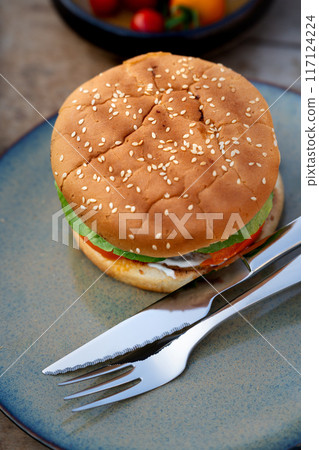 Close up of plate with homemade grilled hamburger and cutlery. Summer outdoor barbecue. Close up of plate with homemade grilled hamburger and cutlery. Summer outdoor barbecue. 117124224