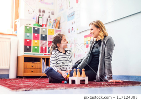 Hardworking teacher learning with young schoolgirl in classroom, explaining topic, using education tools. Hardworking teacher learning with young schoolgirl in classroom, explaining topic, using education tools. 117124393