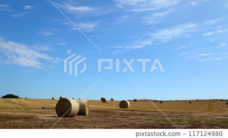 Blue sky with floating clouds and straw roll 117124980