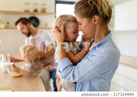 Little girl crying and screaming, mother holding her in arms and soothing her. 117124999
