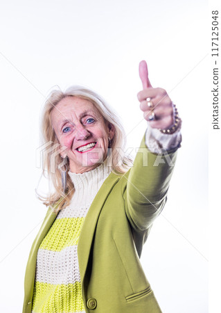 Portrait of a confident and cheerful senior woman smiling and giving a thumbs up gesture 117125048