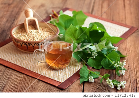 Herbal tea made from buckwheat seed, lat. Fagopyrum esculentum, fresh flowering plant next to it. Herbal tea made from buckwheat seed, lat. Fagopyrum esculentum, fresh flowering plant next to it. 117125412