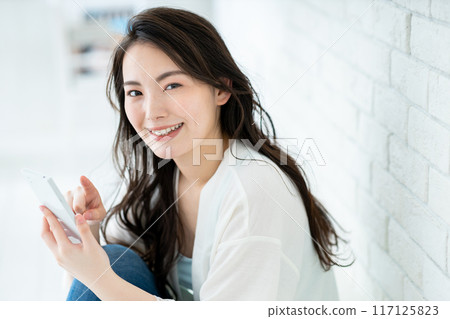 A young woman operating a smartphone 117125823