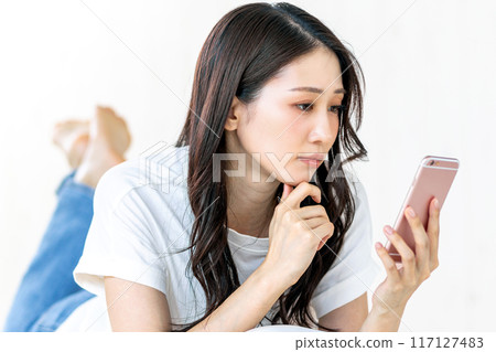 一位女士板著臉看著她的智慧型手機 117127483