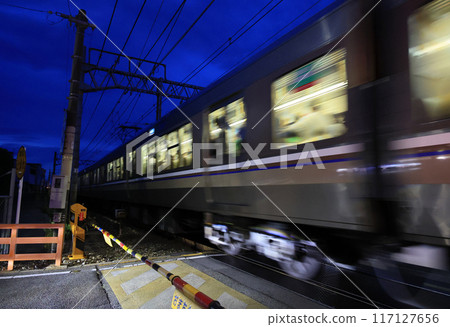 A train passing through a railroad crossing at night 117127656