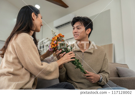 Romantic Couple Sharing a Tender Moment with Flowers in a Cozy Modern Home Setting 117128002