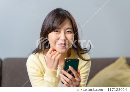 A smiling woman holding a smartphone A smiling woman holding a smartphone 117128024