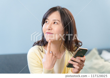 A smiling woman holding a smartphone A smiling woman holding a smartphone 117128025