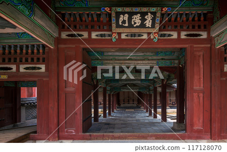 Binyangmun Gate of Changgyeonggung Palace. Shows an open wooden doors leading to a hall, with intricate patterns and traditional architecture, and a sign in Korean above. 117128070