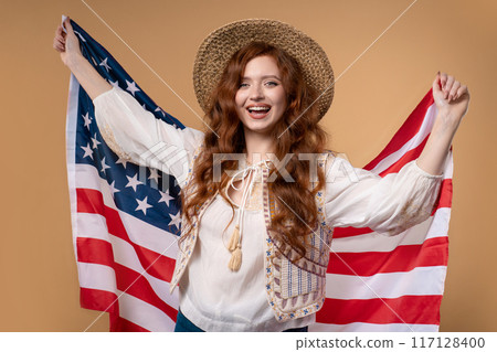 Smiling woman with national USA flag on beige background. American patriot, 4th of July - Independence day celebration, election, America, labor. US banner. Smiling woman with national USA flag on beige background. American patriot, 4th of July - Independence day celebration, election, America, labor. US banner. 117128400