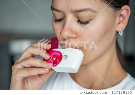Close up view of woman using medicine dry powder inhaler for treatment asthma or COPD diseases. Pharmaceutical product is used to treat lung inflammation and prevent asthma attack. 117129130
