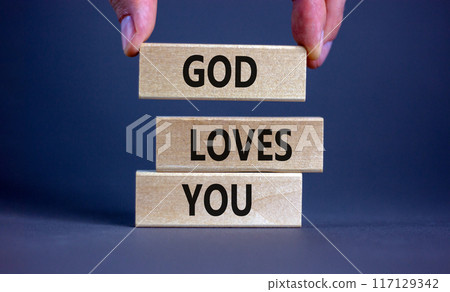 God loves you symbol. Concept words 'God loves you' on wooden blocks on a beautiful grey background, prayer hand. Copy space. Religion and God loves you concept. 117129342