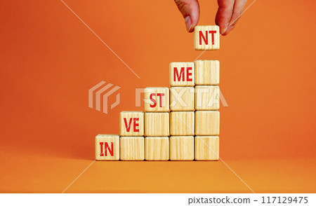 Investment symbol. Concept word Investment on beautiful wooden cubes. Beautiful orange background. Businessman hand. Business investment concept. Copy space. 117129475