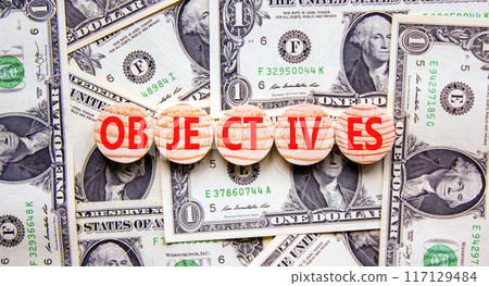 Objectives symbol. Concept word Objectives on beautiful wooden circles. Dollar bills. Beautiful background from dollar bills. Business objectives concept. Copy space. Objectives symbol. Concept word Objectives on beautiful wooden circles. Dollar bills. Beautiful background from dollar bills. Business objectives concept. Copy space. 117129484