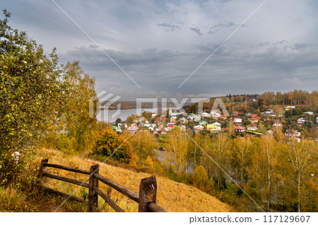 View of the autumn Plyos and Varvarinskaya church from the height of the Cathedral Mountain from behind a wooden fence 117129607