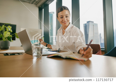 A Professional Woman Engaged in Work Within a Contemporary Office Environment Setting 117130717