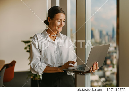 A Professional Woman Working Diligently on Her Laptop in a Modern Office Environment A Professional Woman Working Diligently on Her Laptop in a Modern Office Environment 117130751