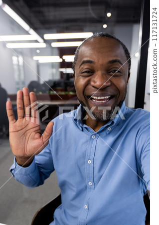 Mature African American office worker using phone for video call. Professional setting inside modern office with bright lighting. Business communication and remote work concept. Mature African American office worker using phone for video call. Professional setting inside modern office with bright lighting. Business communication and remote work concept. 117131724