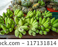 Raw bananas in green color and pumpkins put on merchandise shelf for selling. 117131814