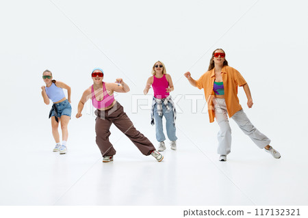 Dressed in bright, casual outfits and sunglasses, four dancers pose with enthusiasm against white studio background. 117132321