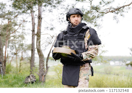 A man in a special suit works with a detector and found an explosive device. A man tries to neutralize an anti-tank mine 117132548