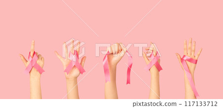 Breast Cancer Awareness Month in October. Group of women hands holding satin pink ribbon awareness to support and fight for health. Breast cancer screening and prevention campaign banner. 117133712