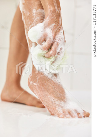 Woman washing her legs with foam bubbles and bath sponge while taking shower in the bathroom Woman washing her legs with foam bubbles and bath sponge while taking shower in the bathroom 117133773
