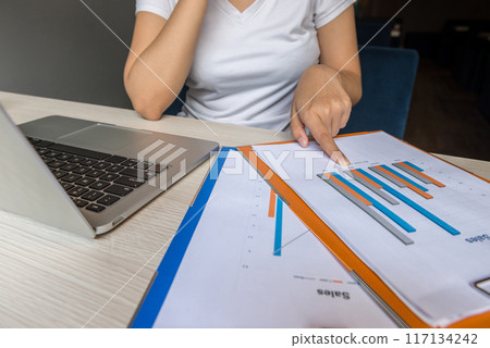 Close up of woman finger pointing at sales chart report 117134242