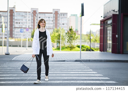Young woman in formal clothes walking near grey wall outdoors, space for text Young woman in formal clothes walking near grey wall outdoors, space for text 117134415