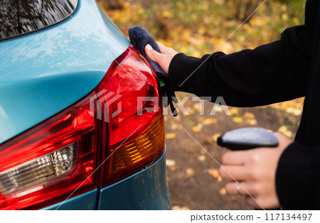 Closeup picture, image young woman, driver, dry wiping her car with microfiber cloth after washing it, cleaning auto, automobile windows. Transportation self service, care concept. Paint protection 117134497