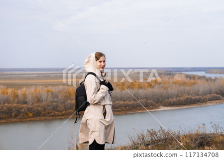 A woman stands on the edge of a cliff and looks at a nearby island, the sea. Unity with nature. A woman stands on the edge of a cliff and looks at a nearby island, the sea. Unity with nature. 117134708