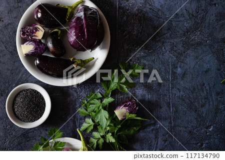 Assortment raw organic of purple vegetables mini eggplants, spring onion, beetroot, radicchio salad, plums, kohlrabi, flower salt over dark metal background. Top view with space. Food frame 117134790