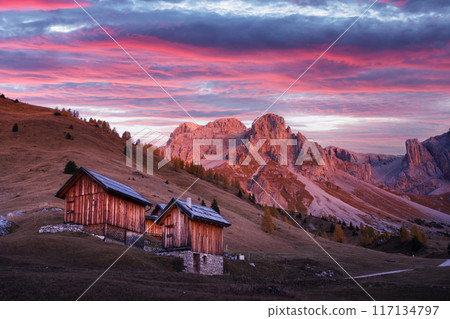Wooden cabins, orange larches and mountains peaks Wooden cabins, orange larches and mountains peaks 117134797